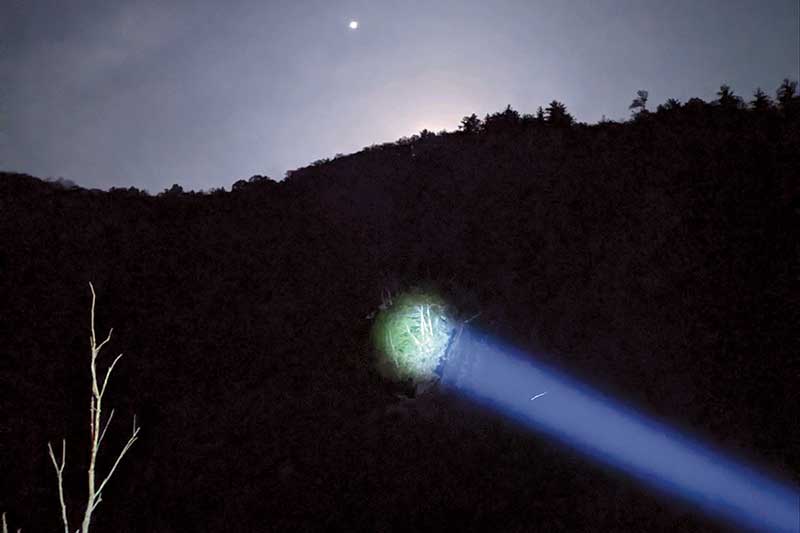 Photo submitted - A spotlight shines on the area where the man was located. This photo was taken at about 4:30 a.m. – the moon is just below the horizon and the dot that looks like a star is the Macon County drone that was used in the search and rescue operation.