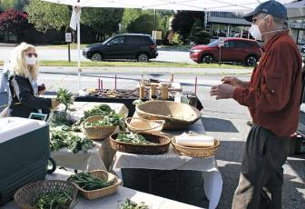 Press photo/Andy Scheidler - Vendor Paul Chew talks to customer Debi Gedling while she purchases produce at the Franklin Farmers Tailgate Market.