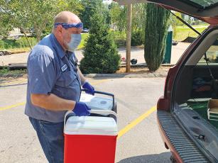 Press photo/Will Woolever - Crawford Center employee Coleman Buchanan unloads empty coolers from a drivers’ vehicle. Drivers deliver hot meals to Macon County seniors who are unable to pick them up at the drive-through five days a week.