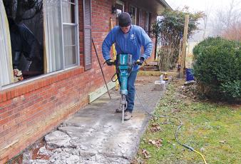 Submitted photo/Habitat - John Wert of Habitat for Humanity removes a sidewalk at Vaughn Sanders’ home as part of the Healthy Home Initiative. The sidewalk was sunken and too narrow for Sanders’ wheelchair, so the construction crew replaced it with a front porch and ramp.