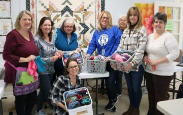Press photo/Anissa Holland - Volunteers for Warmth on Wheels met in the classroom at A Stitch In Time to continue making hats and mittens for elementary school bus riders. 