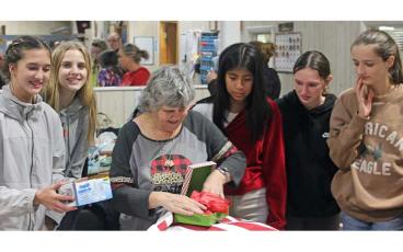 Press photo/Thomas Sherrill - Students watch as a Macon Citizens Habilities resident opens one of many Christmas presents delivered as part of an gift-giving event on Dec. 14.