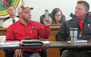Press photo/Thomas Sherrill - Macon County Schools Maintenance Director Tracy Tallent (left) shows a piece of galvanized pipe cut out of Macon Middle School during a presentation on the sewer vent pipes at Friday morning’s special school board meeting. Next to Tallent is Franklin High Principal Mickey Noe.