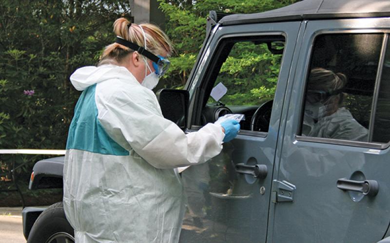 Photo/Ryan Hanchett A health care worker conducts a test for COVID-19 during drive-thru testing on June 4 in Highlands.