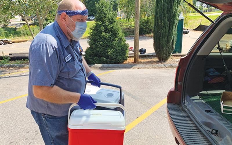Press photo/Will Woolever - Crawford Center employee Coleman Buchanan unloads empty coolers from a drivers’ vehicle. Drivers deliver hot meals to Macon County seniors who are unable to pick them up at the drive-through five days a week.