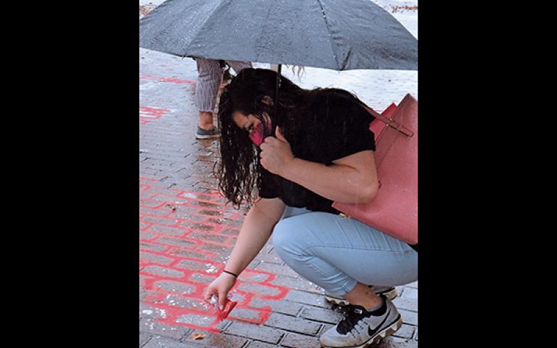 Press photo/Linda Mathias - Kuteka Lopez pours red sand outside the Macon County Courthouse to draw attention to victims of human trafficking.