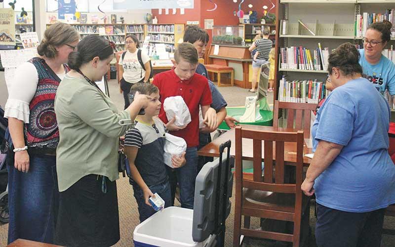 Press photo/Thomas Sherrill - Macon County Schools staffers hand out free lunches and milk cartons to kids at the Macon County Public Library after a program. Kids receive free lunches at 11 a.m. every weekday at the library through Aug. 2.